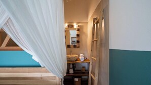A bedroom with a wooden bunk bed, a bedside table with a lamp, and a mirror above the sink.