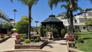 Un jardin agrémenté d’un kiosque, de palmiers et d’un espace piscine.