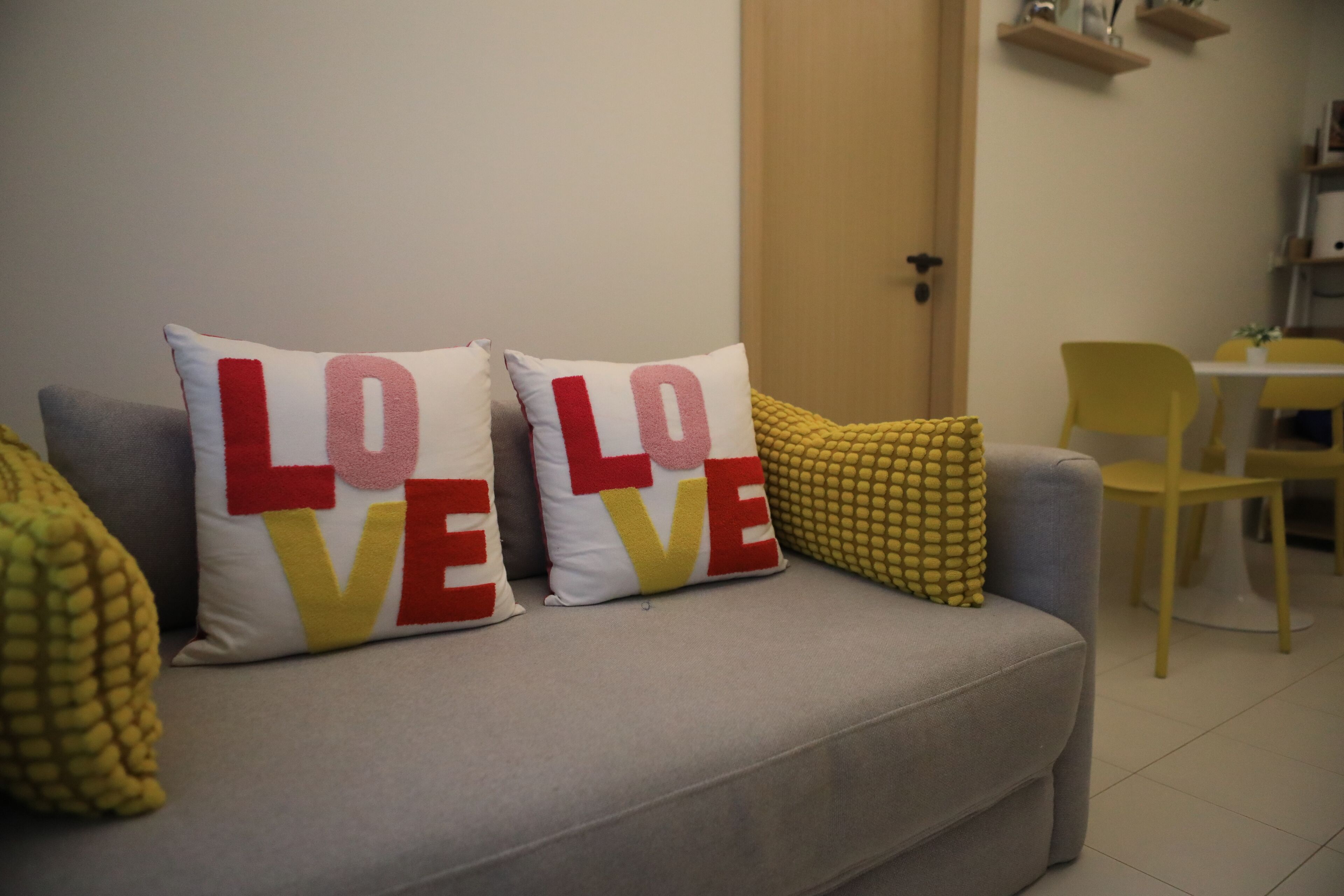 Un sofá gris con tres cojines decorativos, uno con la palabra 'LOVE' en letras negritas.