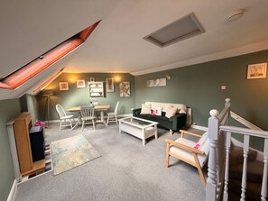 Ein Loft-Wohnzimmer mit schräg verlaufender Decke, einem Essbereich und einer Treppe.
