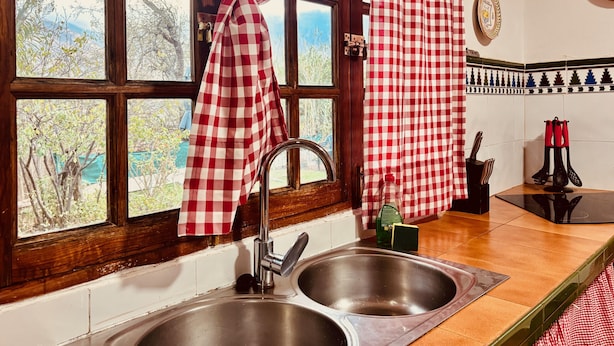 A kitchen with a double sink, a window with checkered curtains, and a tiled backsplash. - Los Almendros. (Valsequillo)