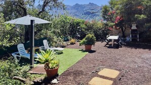 A patio area with a table and chairs, a potted plant, and a view of mountains. - Los Almendros. (Valsequillo)