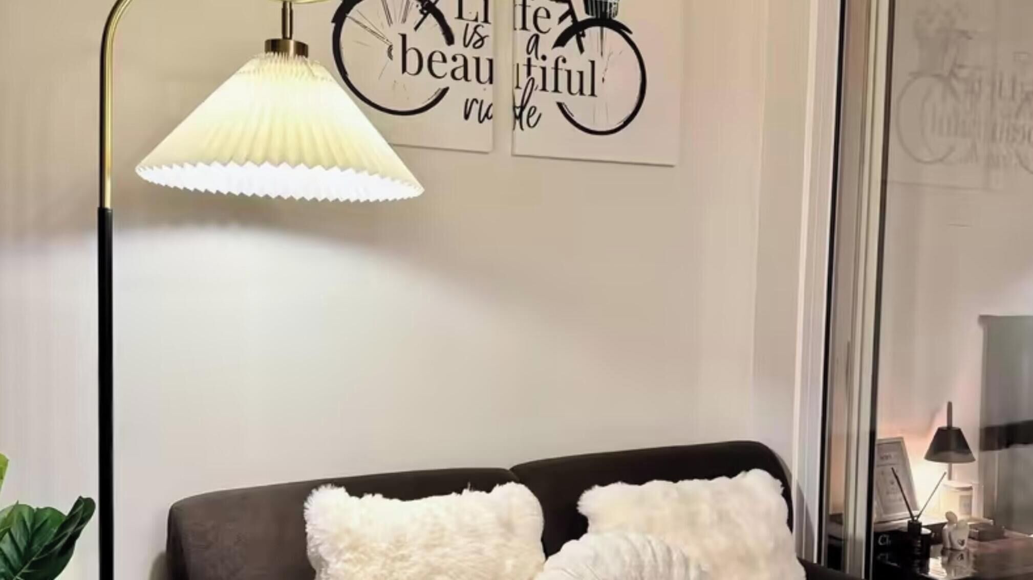A room with a bed, a floor lamp, and a wall with motivational quotes.