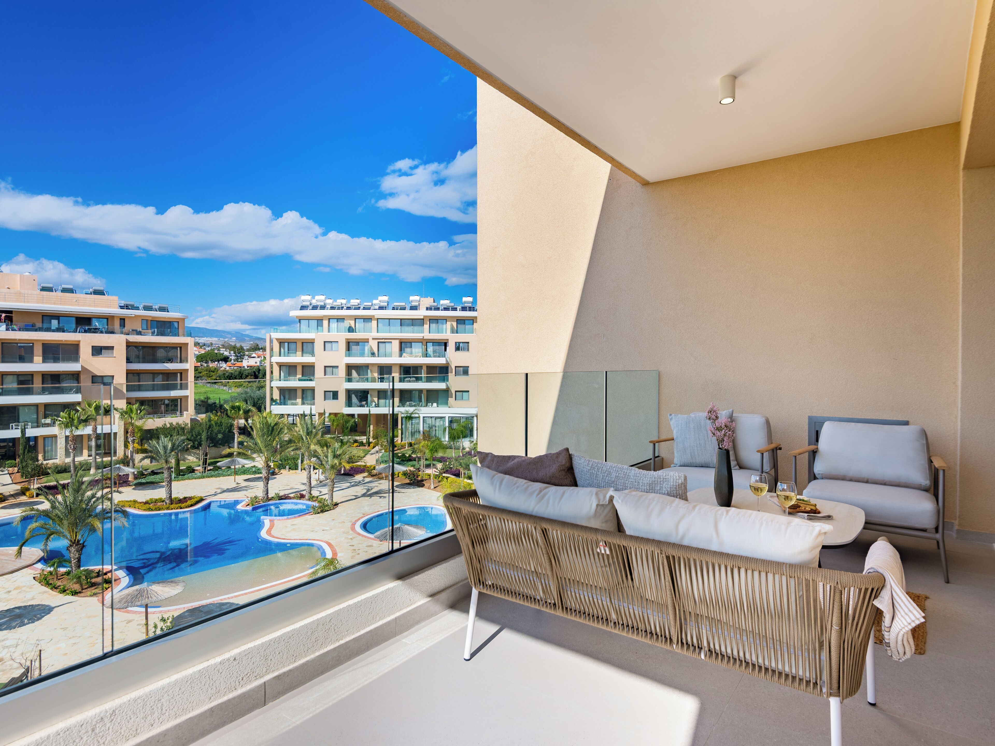 A modern hotel room with a balcony overlooking a swimming pool and other buildings.