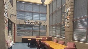 A spacious dining area with a long wooden table and multiple chairs, large windows with blinds, and decorative wall art. - Enkipai Hill Hotel (Narok)