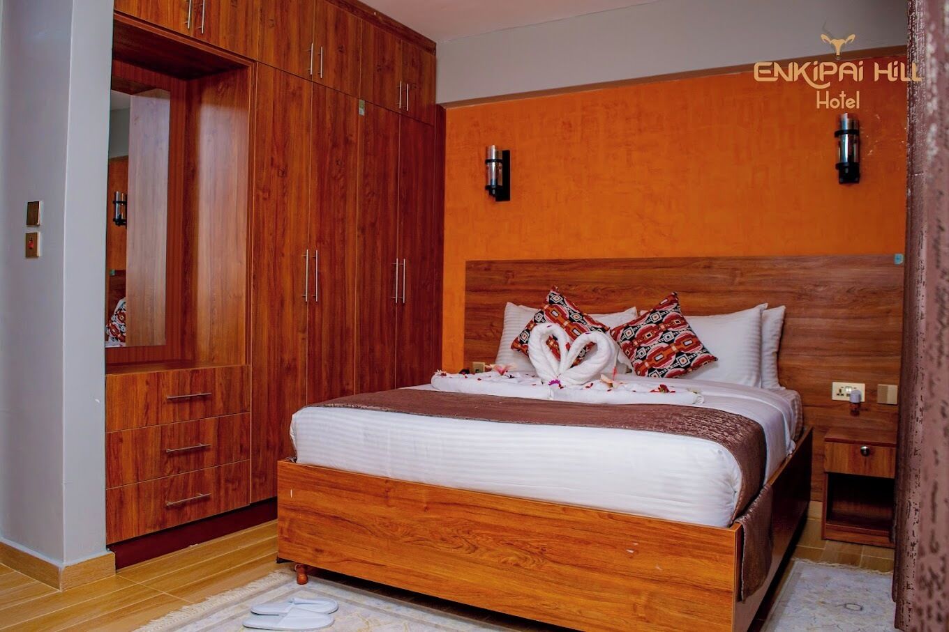 A hotel room with a wooden bed, a wardrobe, and a nightstand.