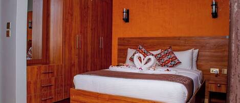 Una habitación de hotel con una cama de madera, un armario y una mesita de noche.