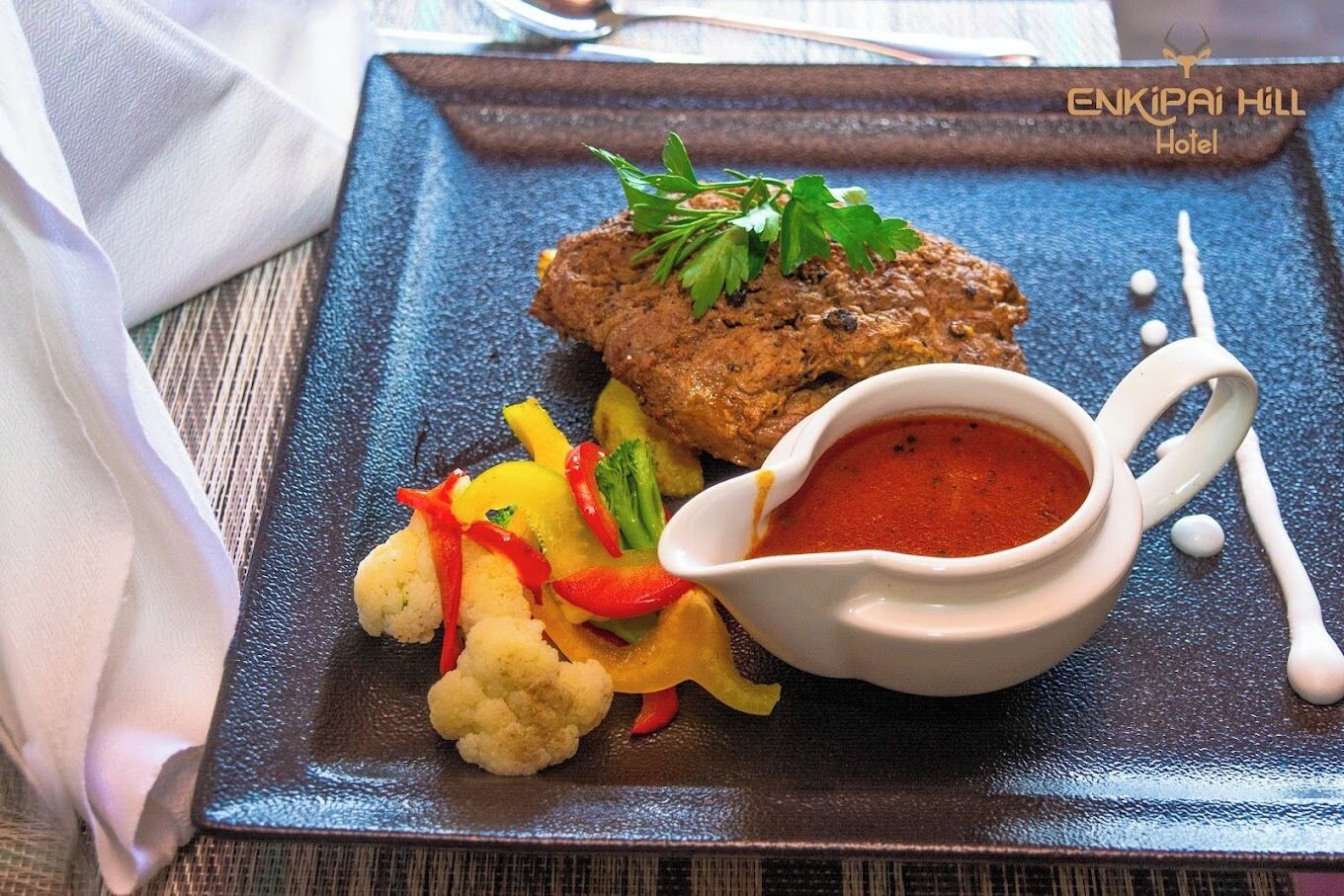 Ein Teller mit einem Fleisch-Patty, Gemüse und Soße.