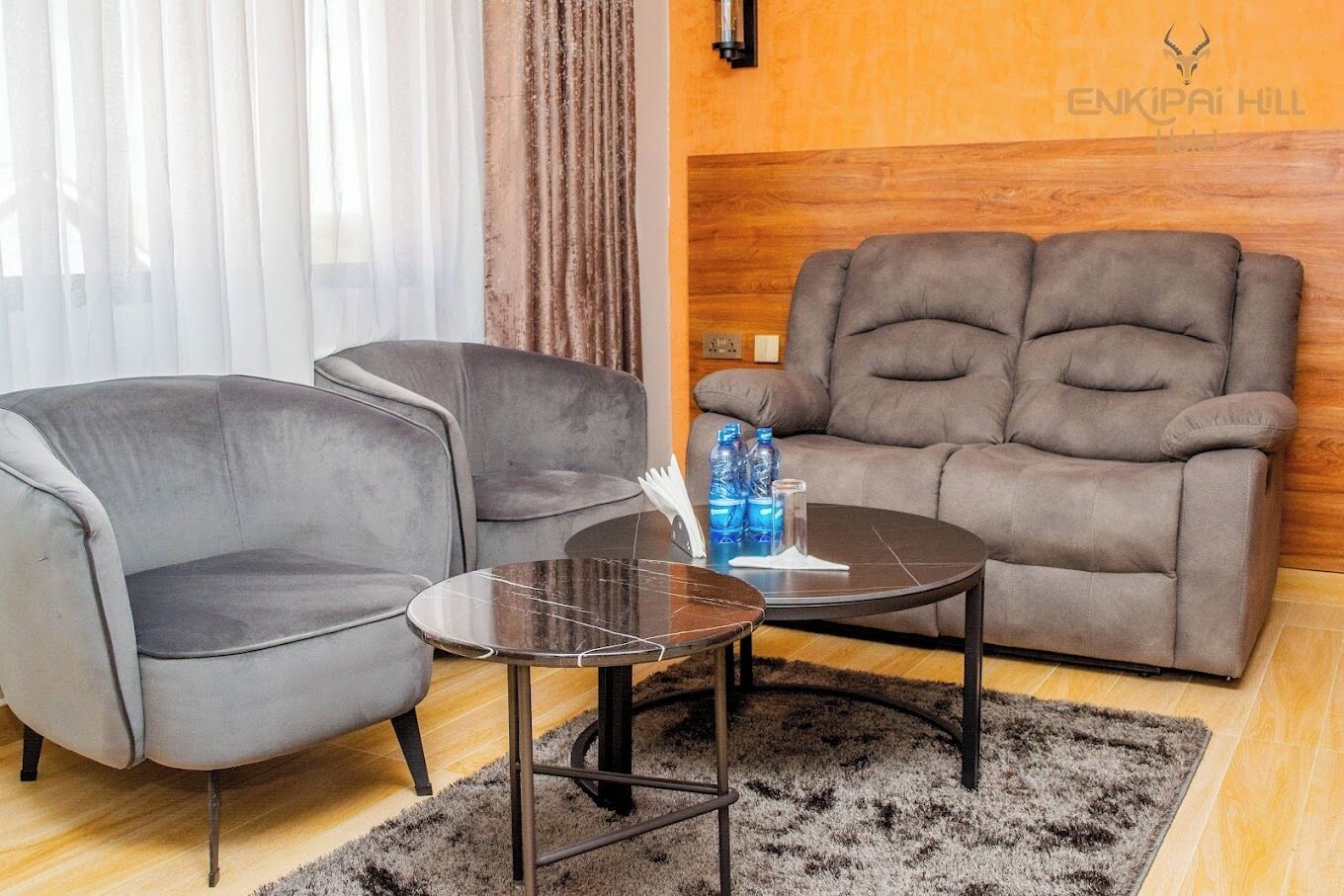 A modern living room with two grey armchairs, a round coffee table, and a grey sofa.