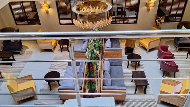 A spacious lobby with multiple seating areas, a central decorative plant, and a chandelier. - Enkipai Hill Hotel (Narok)