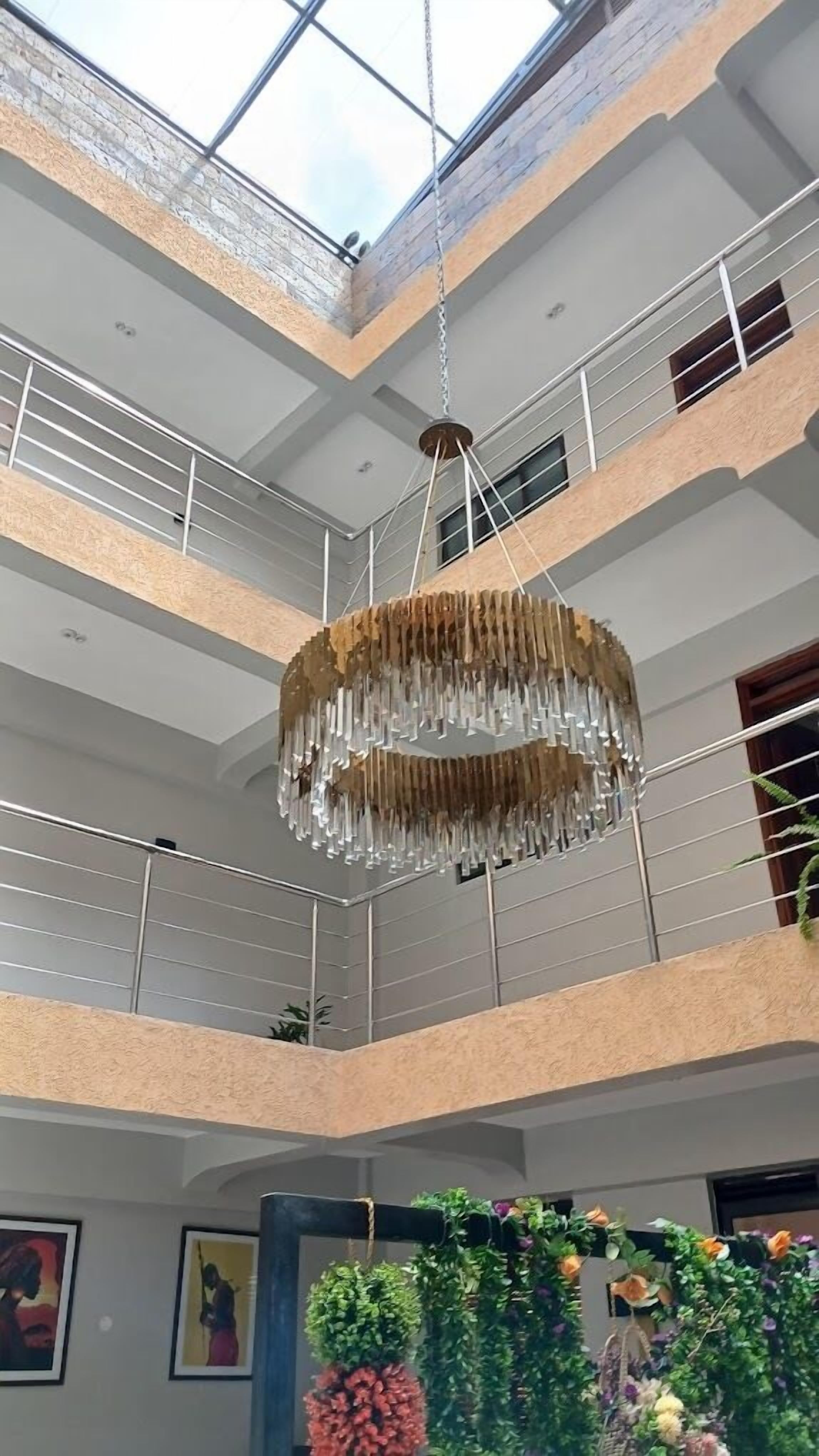A multi-level atrium with a hanging chandelier, balconies, and indoor plants.