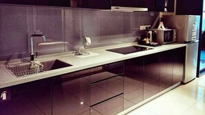 A modern kitchen with a stainless steel refrigerator, a microwave, and a sink with a faucet. - Urbano Luxury Homestay (George Town)