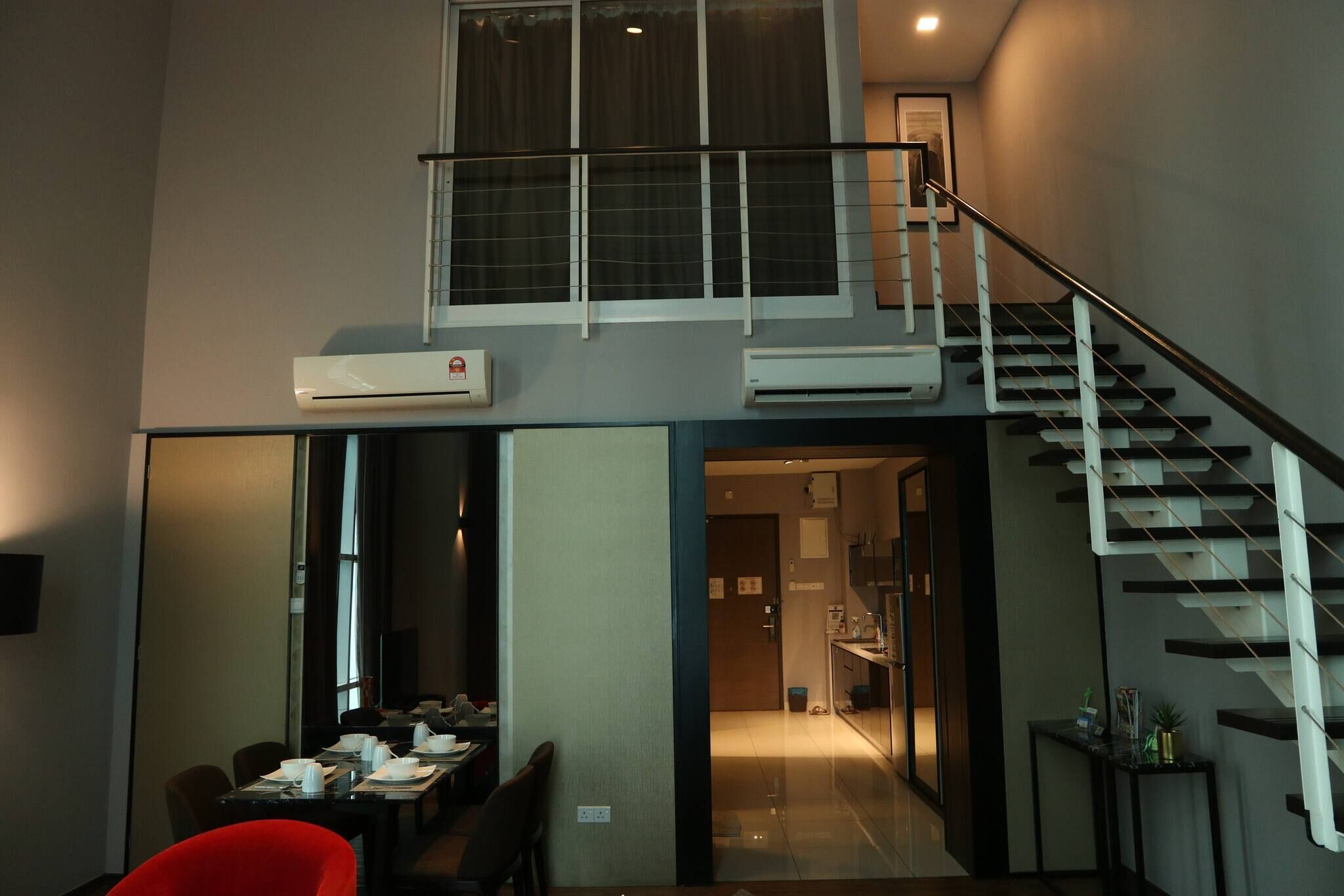 A modern interior with a dining area, a staircase, and an air conditioning unit.
