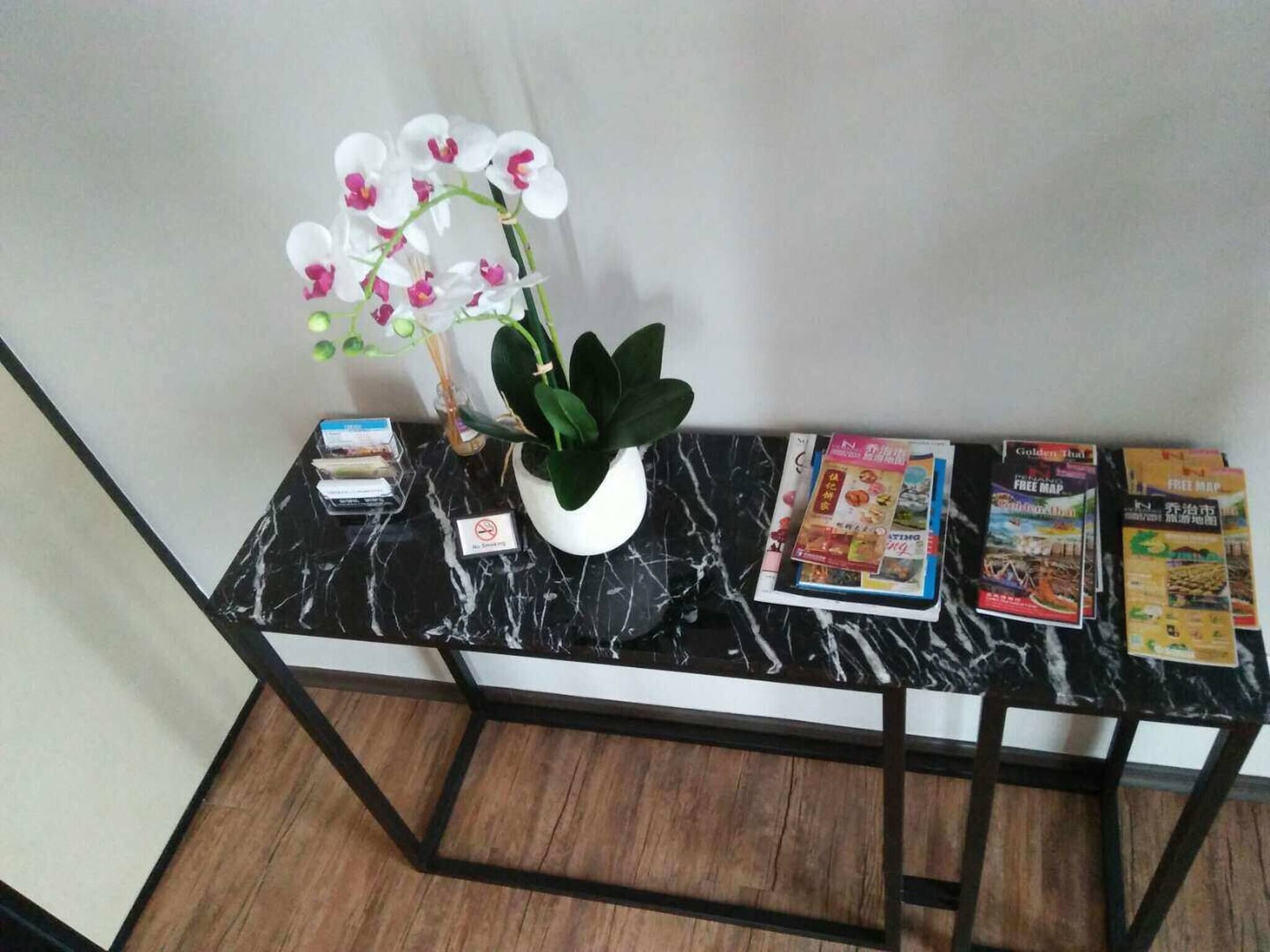 A marble table with a potted orchid, a small sign, and several travel brochures.