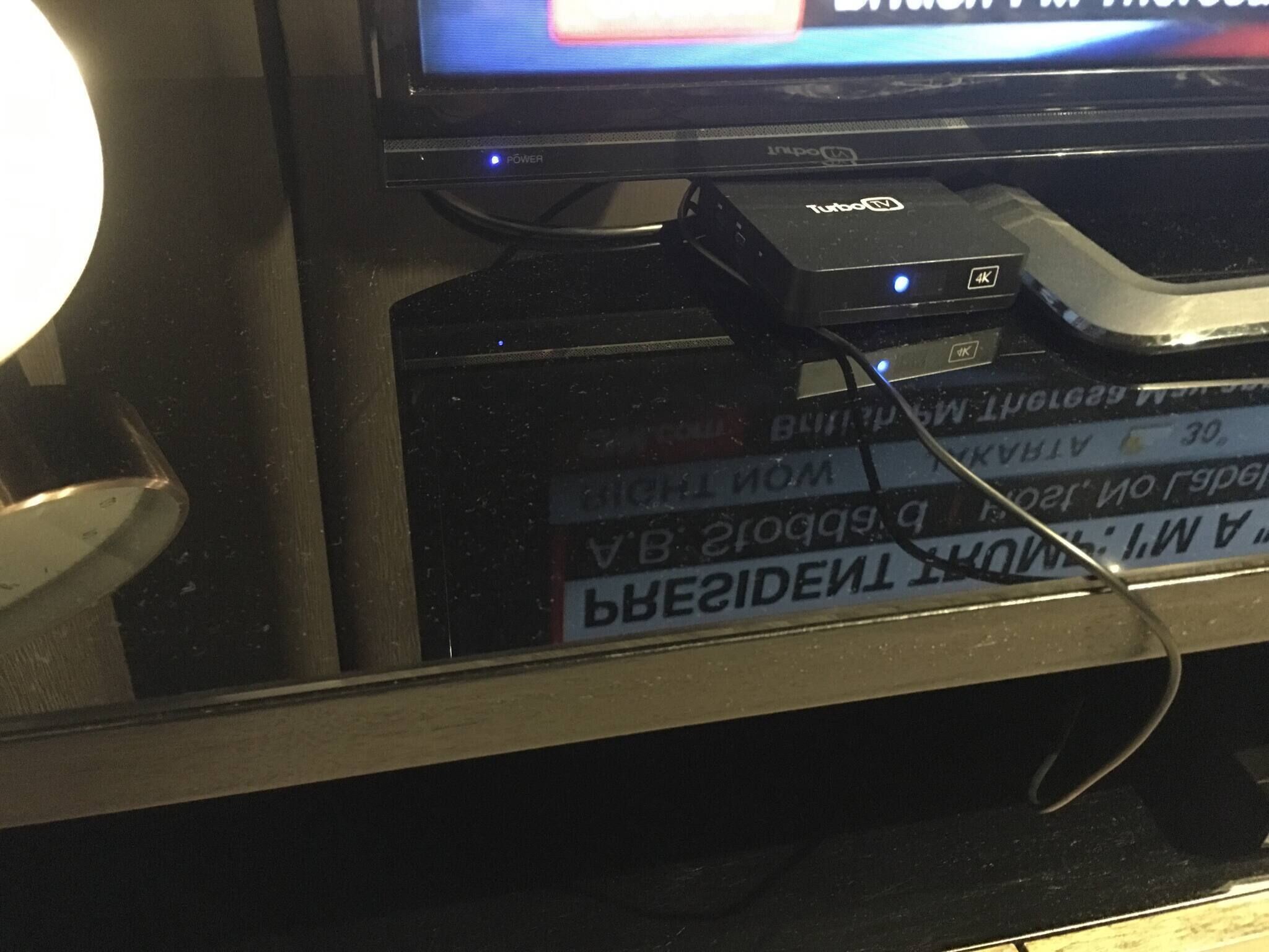 Un televisor con un logotipo visible y un decodificador con etiqueta 4K.