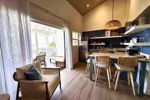Una cocina moderna con zona de comedor, suelo de madera y un amplio ventanal con cortinas.