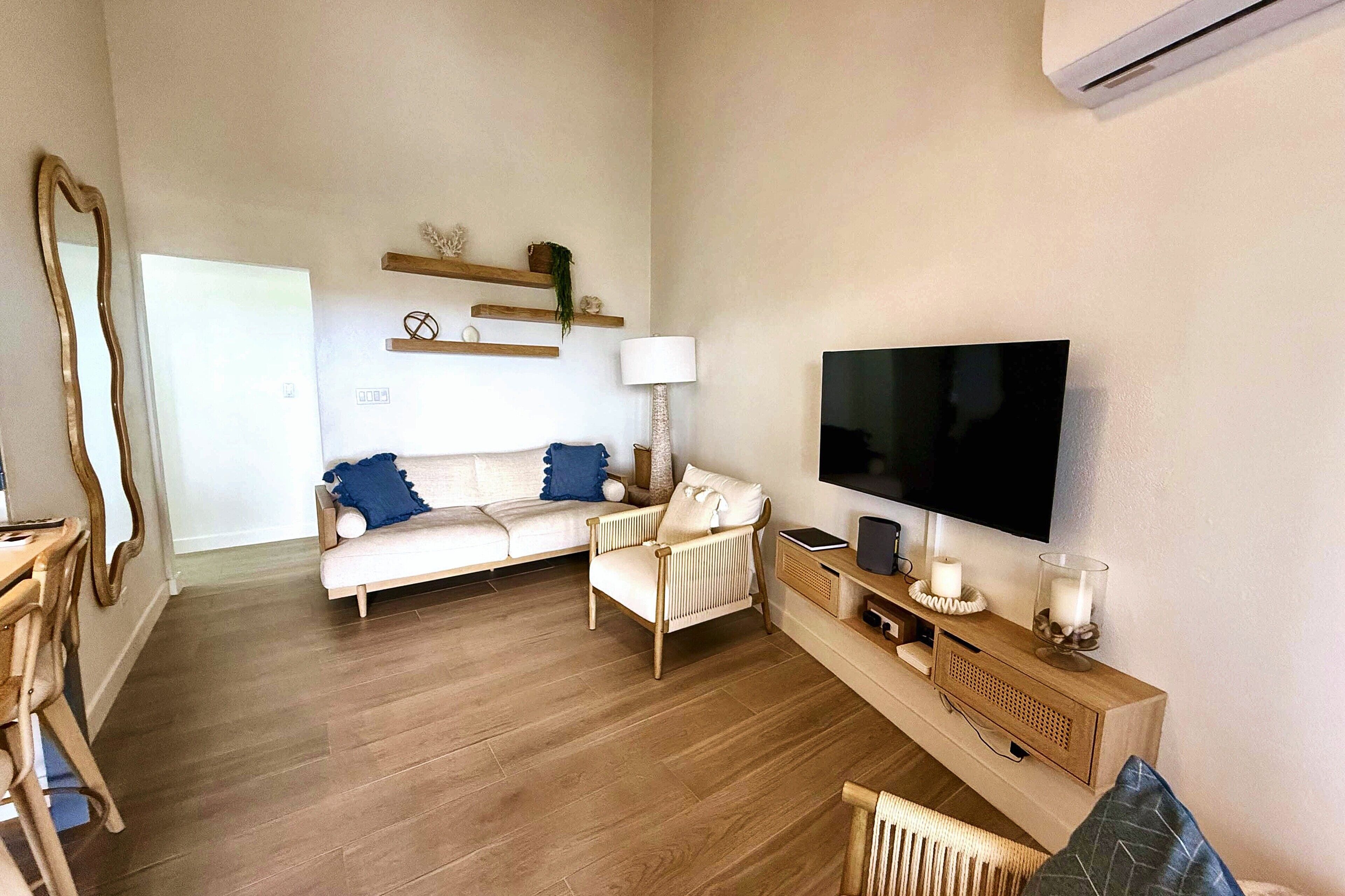 A living room with a sofa, armchairs, a TV, and a wooden cabinet.
