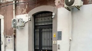 A building with a black gate, air conditioning units, and a water bottle on the sidewalk. - FLORENTINE'S HOUSE  (Catania)