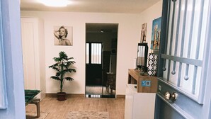 A spacious living area with a wooden floor, a potted plant, and a welcome mat. - FLORENTINE'S HOUSE  (Catania)