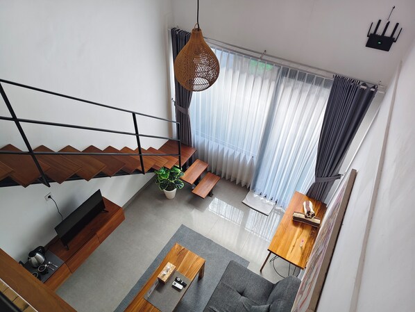 Un salon moderne avec un escalier, un canapé, une table basse et une plante en pot.