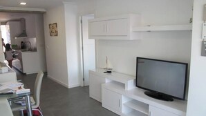 A modern kitchen with white cabinetry, a built-in stove, and a dining area with a table and chairs. - Apartment very seafront beachfront Pobla Farnals beach (La Pobla de Farnals)