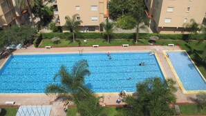 A large rectangular swimming pool with multiple lanes, surrounded by palm trees and a well-maintained lawn. - Apartment very seafront beachfront Pobla Farnals beach (La Pobla de Farnals)