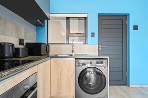 A compact kitchen with a washing machine, a microwave, and a coffee maker. - Blouberg Mews (Cape Town)
