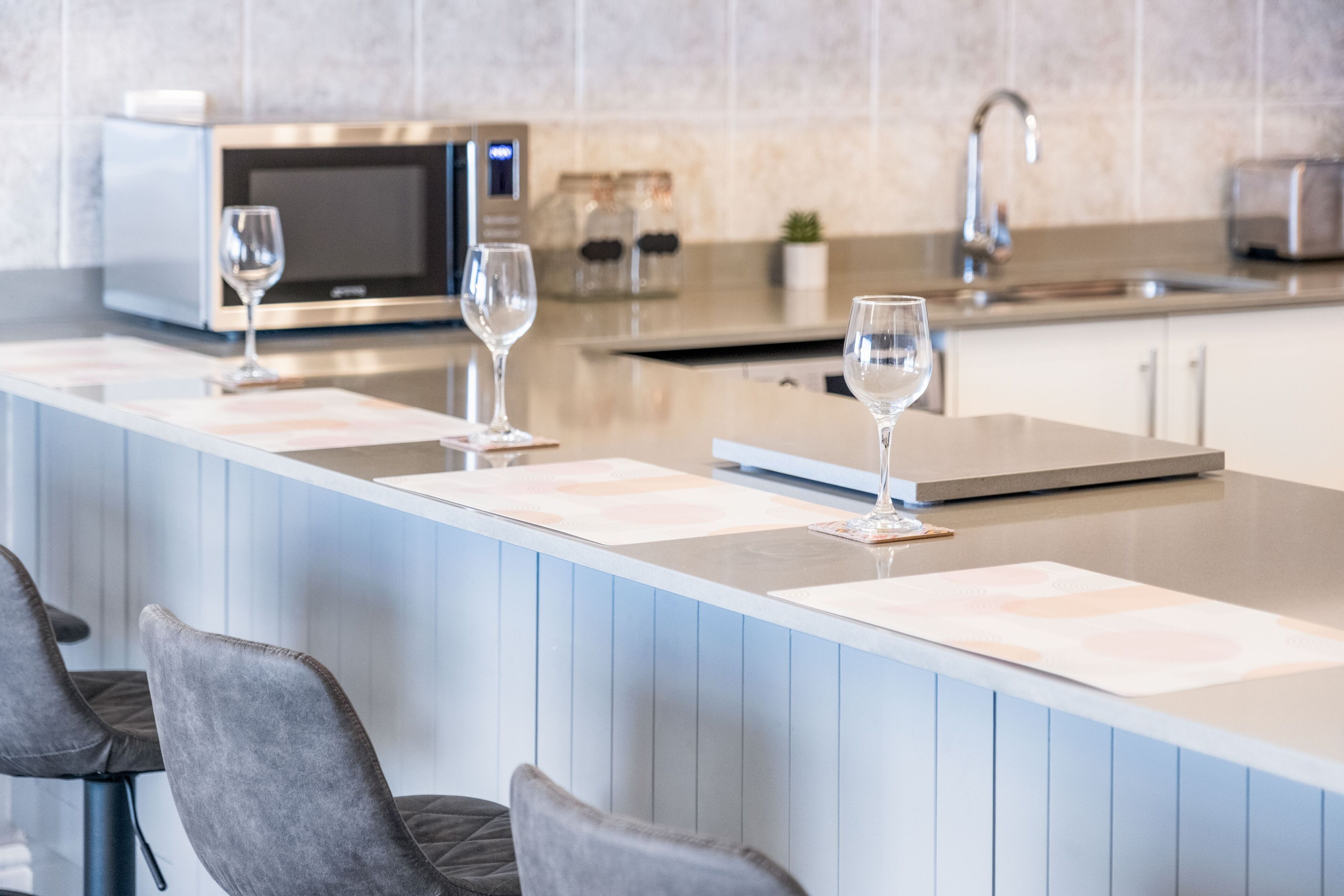 Une cuisine moderne dotée d’un grand îlot central, d’appareils électroménagers en acier inoxydable et de deux tabourets de bar.