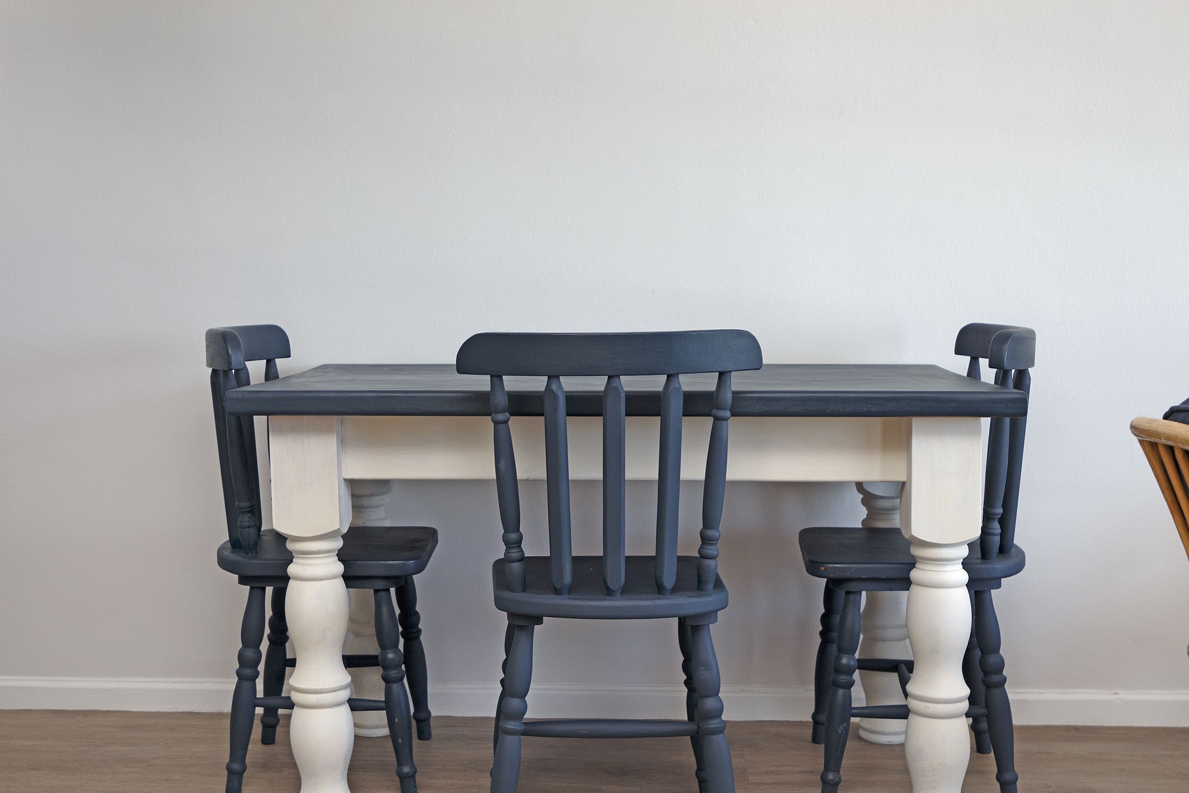 A dining table with four chairs, each with a dark wooden seat and a white base.