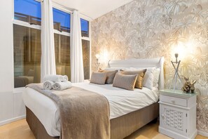 A bedroom with a bed, a nightstand, and a window with curtains. - Horizon Bay 103 (Cape Town)