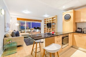 A modern kitchen with a central island, wooden cabinets, and a built-in oven. - Horizon Bay 103 (Cape Town)