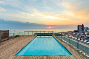 A swimming pool with a wooden deck and a view of the sunset over the ocean. - Horizon Bay 103 (Cape Town)