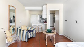 Quarto de hotel compacto com cozinha compacta, um sofá listrado, uma mesa pequena e uma cama.