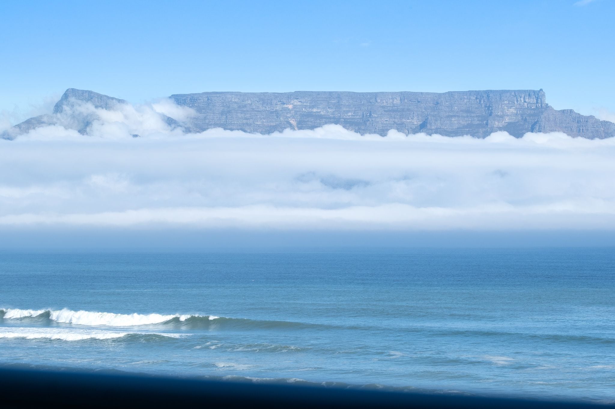 A coastal landscape with a prominent cliff and ocean waves.