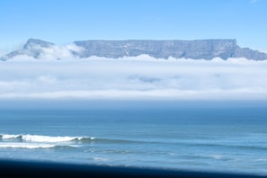A coastal landscape with a prominent cliff and ocean waves. - Sea Spray A410 (Cape Town)