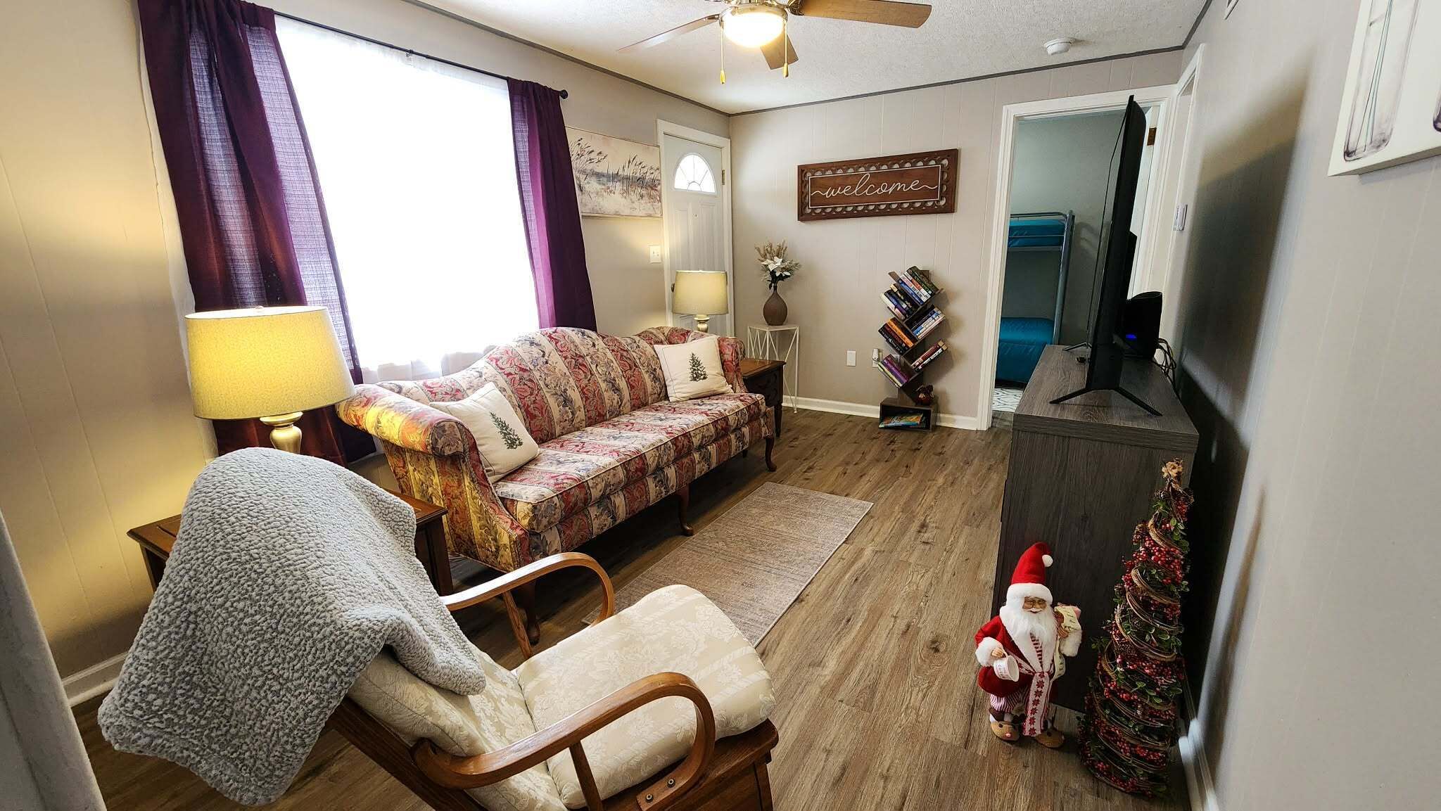 A cozy living room with a patterned sofa, a wooden chair, a television, and a Christmas decoration.