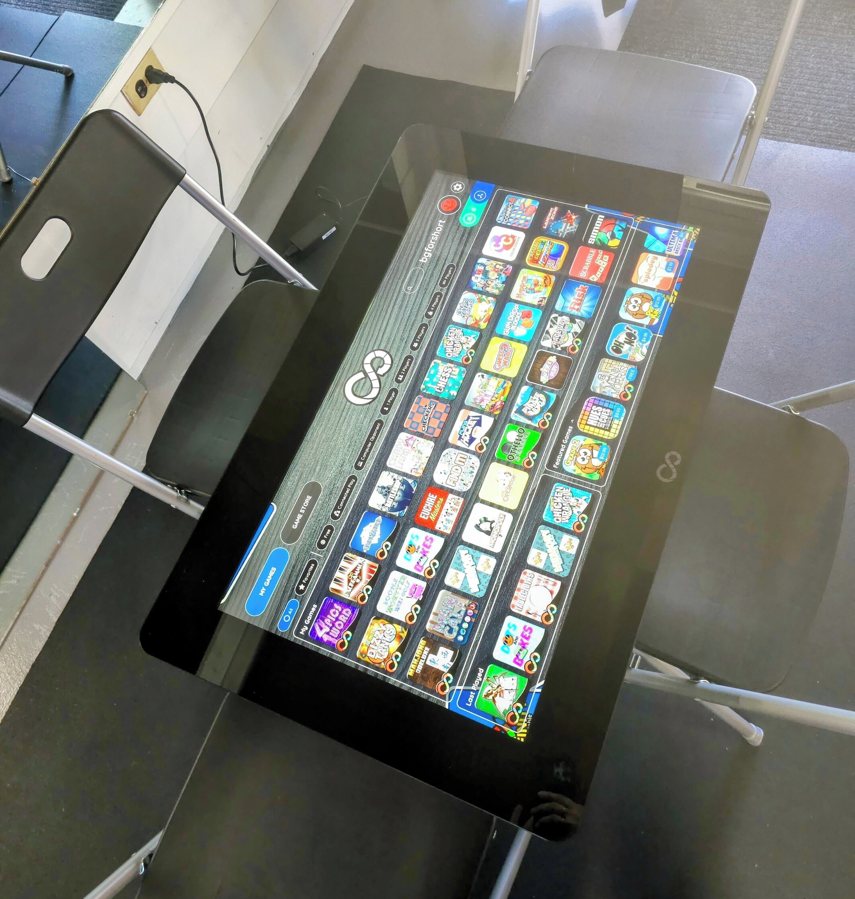Une tablette affiche une variété d’icônes de jeux sur une table.