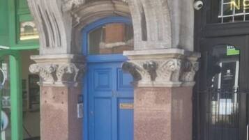 A building facade with a blue door and a sign above it.