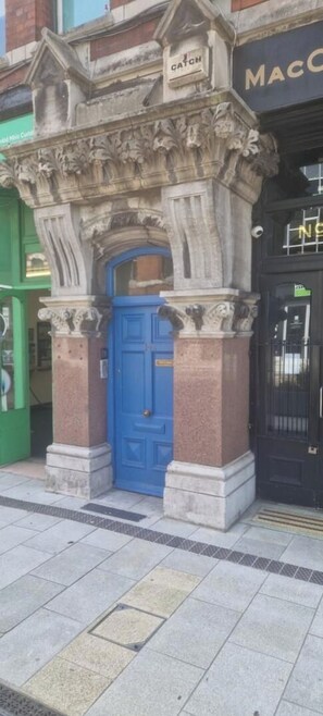 Fachada de un edificio con una puerta azul y un cartel encima.
