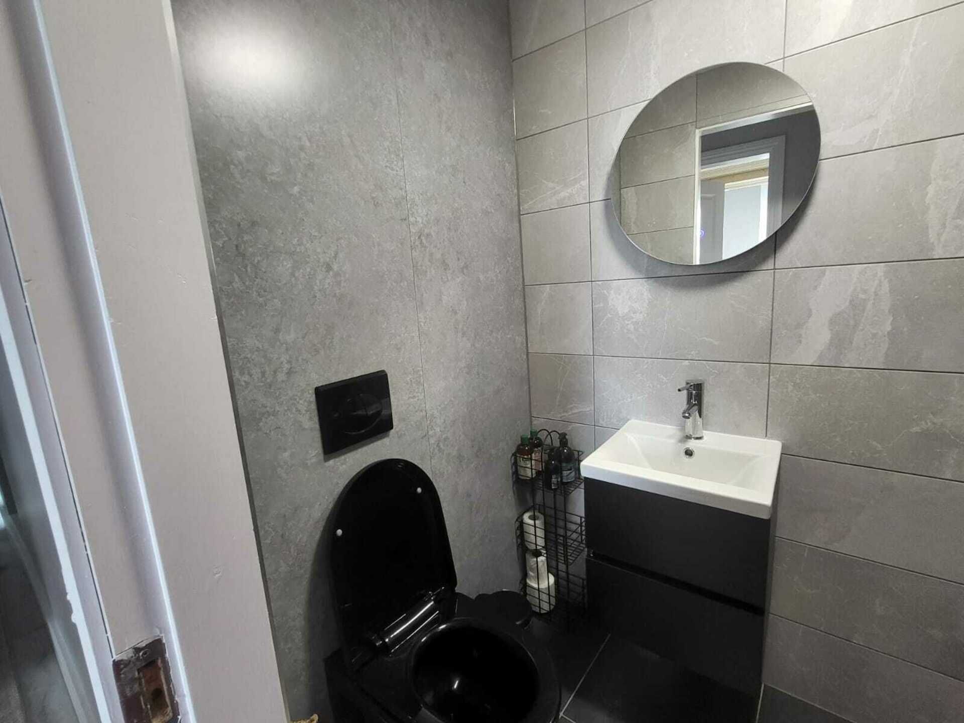 A bathroom with a toilet, sink, and mirror.