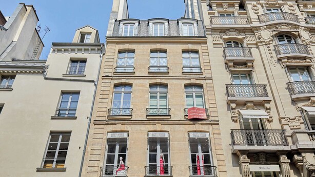 Un immeuble à plusieurs étages, doté d’une architecture riche et ornée, comprenant des balcons et des moulures décoratives.
