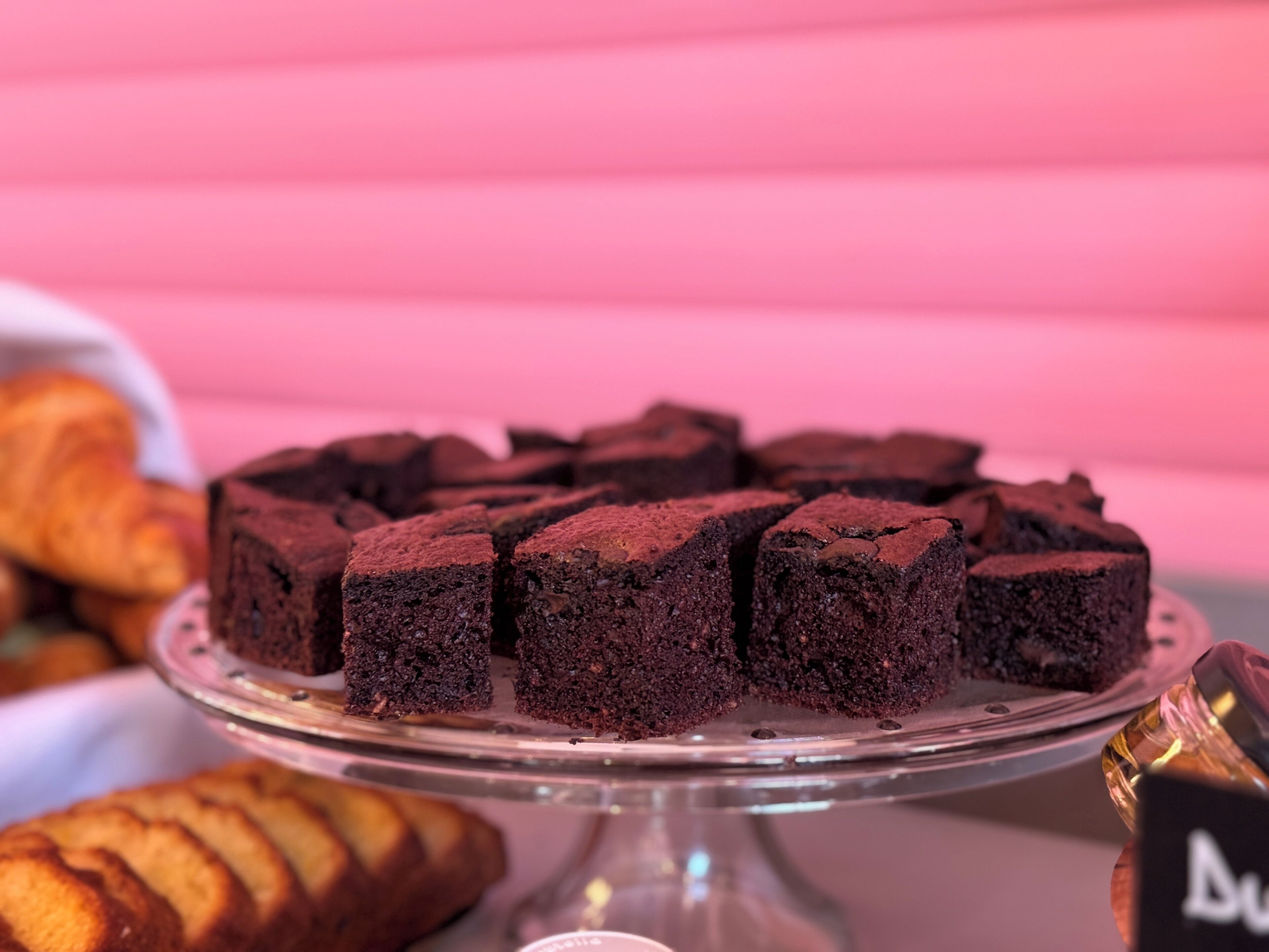 A round cake stand with several square brownies on it.