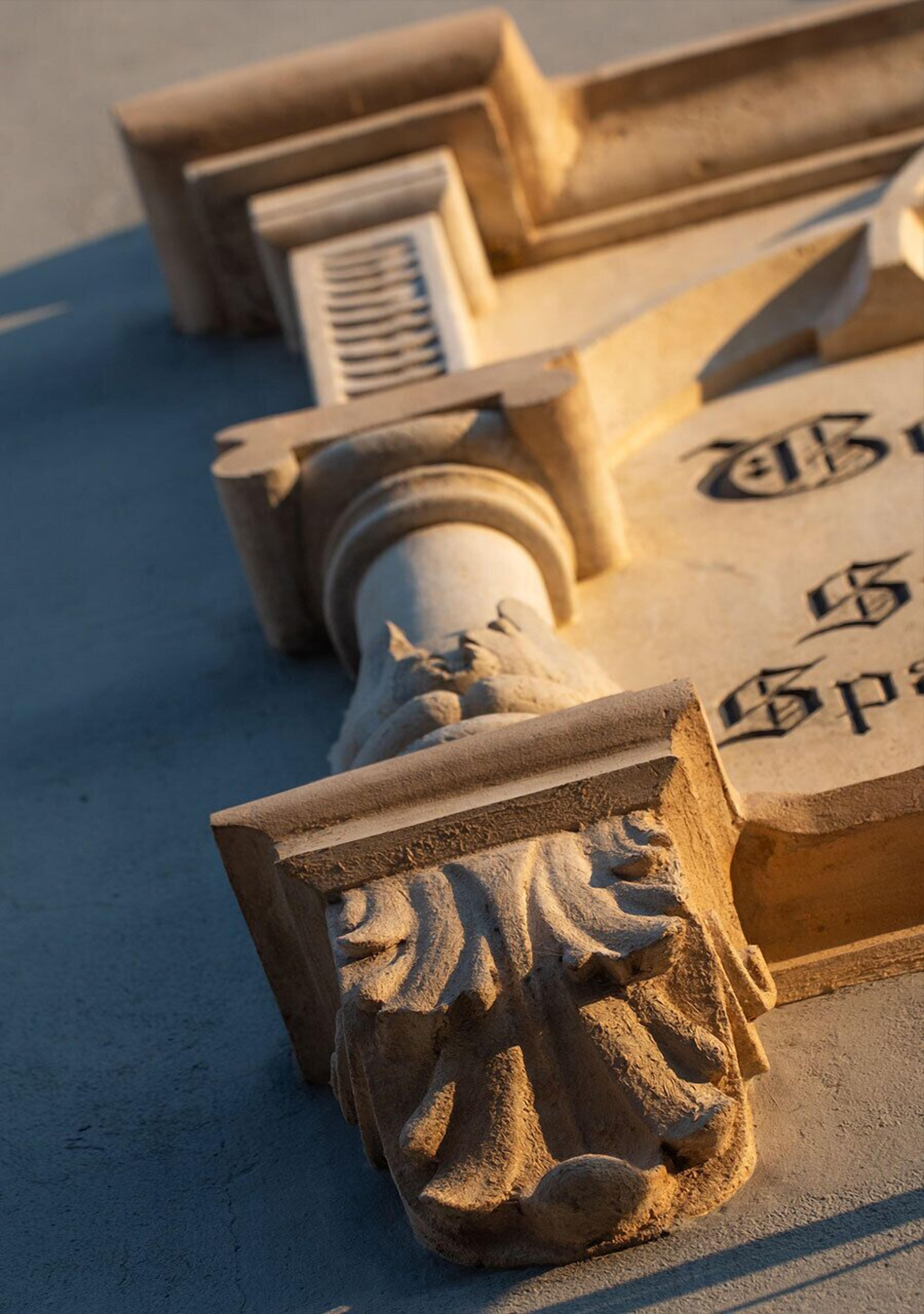 A close-up of a stone architectural detail with carved figures and inscriptions.