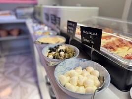 Un bufé con diversas opciones de comida, incluyendo un bol de aceitunas, un bol de queso mozzarella y una bandeja de embutidos cortados.