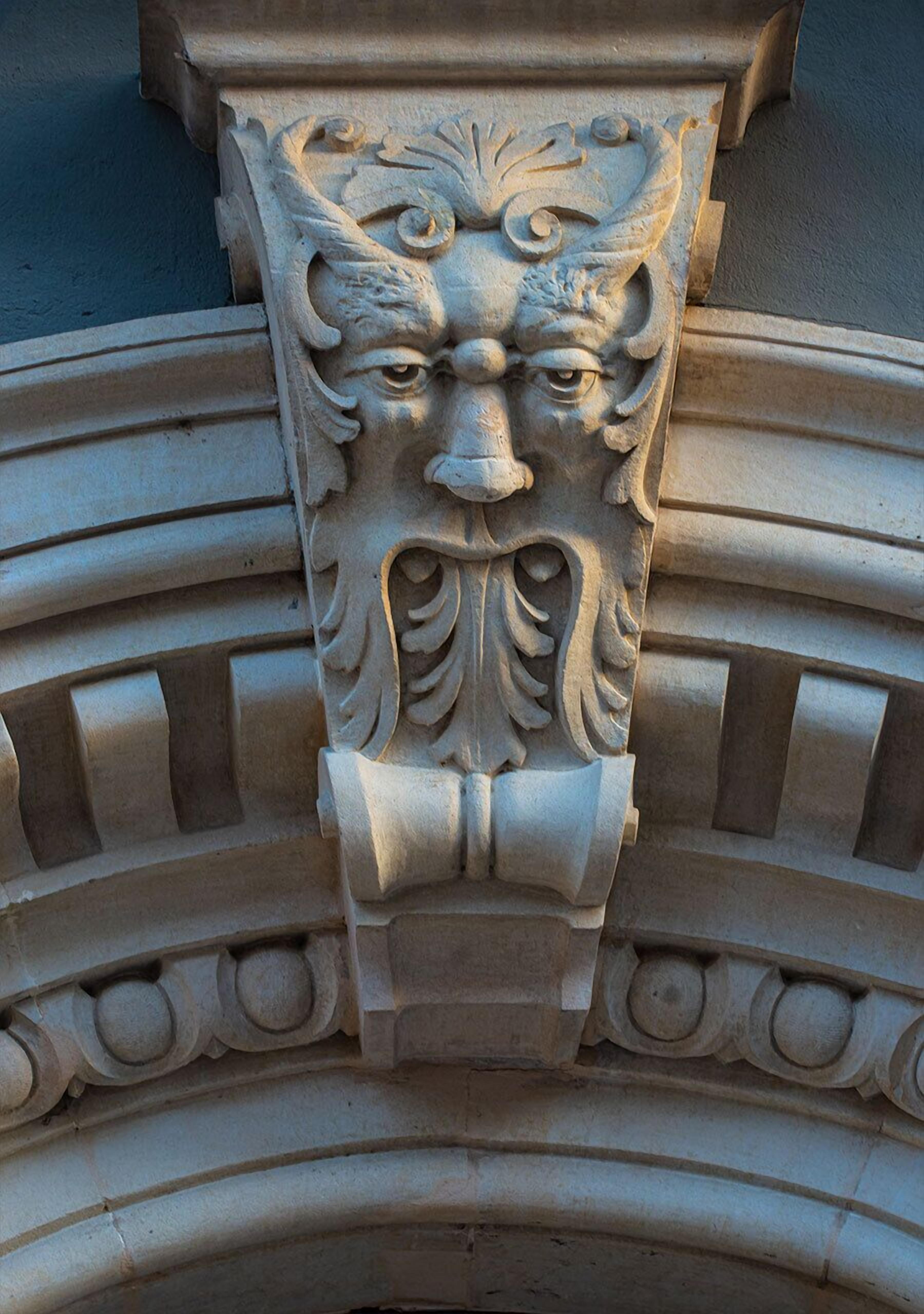 Une sculpture détaillée dans la pierre, ornée de motifs complexes et présentant un motif central évoquant un visage.