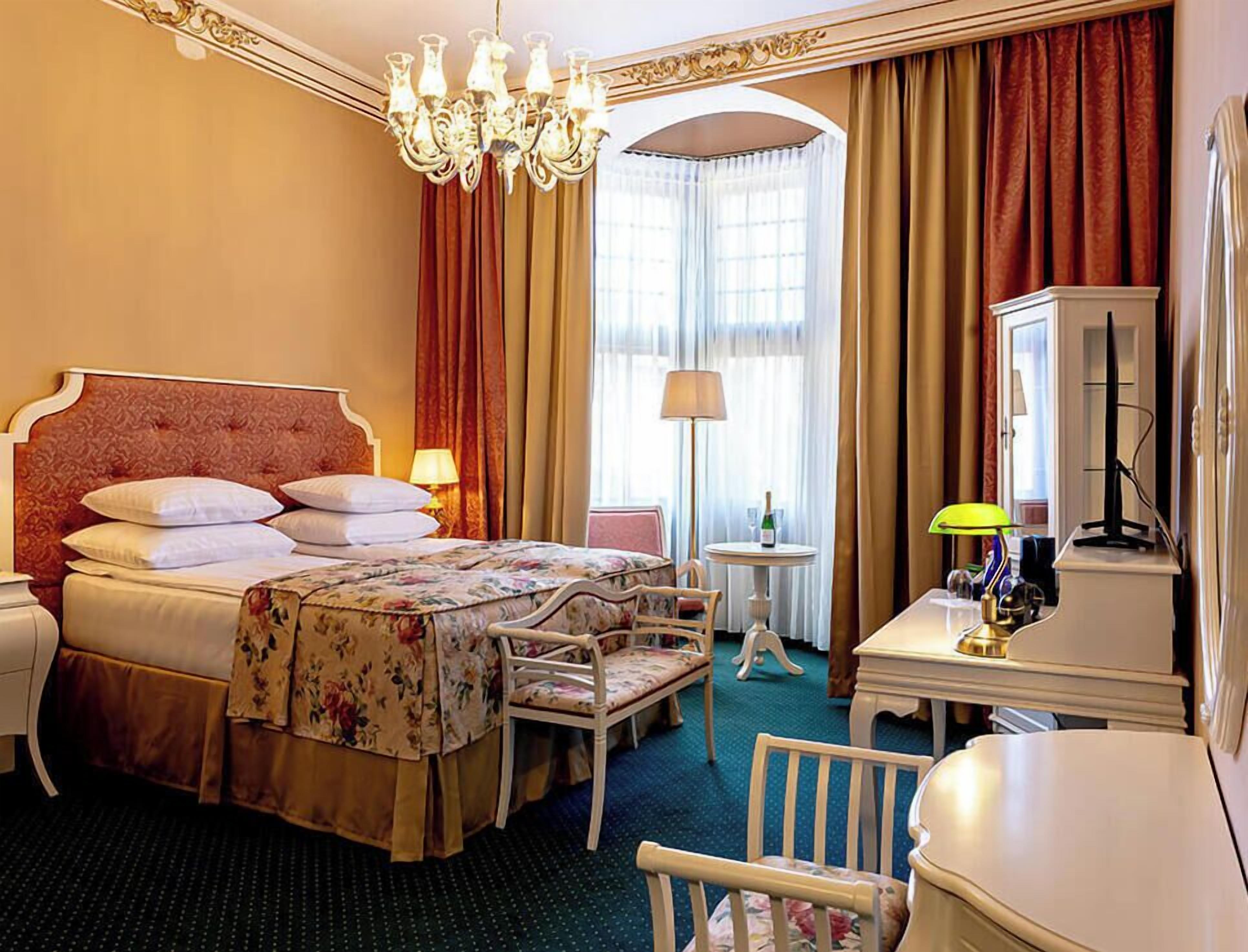 Une chambre d’hôtel avec un grand lit, un bureau, une chaise, une lampe et un téléviseur.