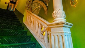 A grand staircase with ornate golden patterns and a white column. - Heritage Boutique Hotel Sighisoara (Sighişoara)
