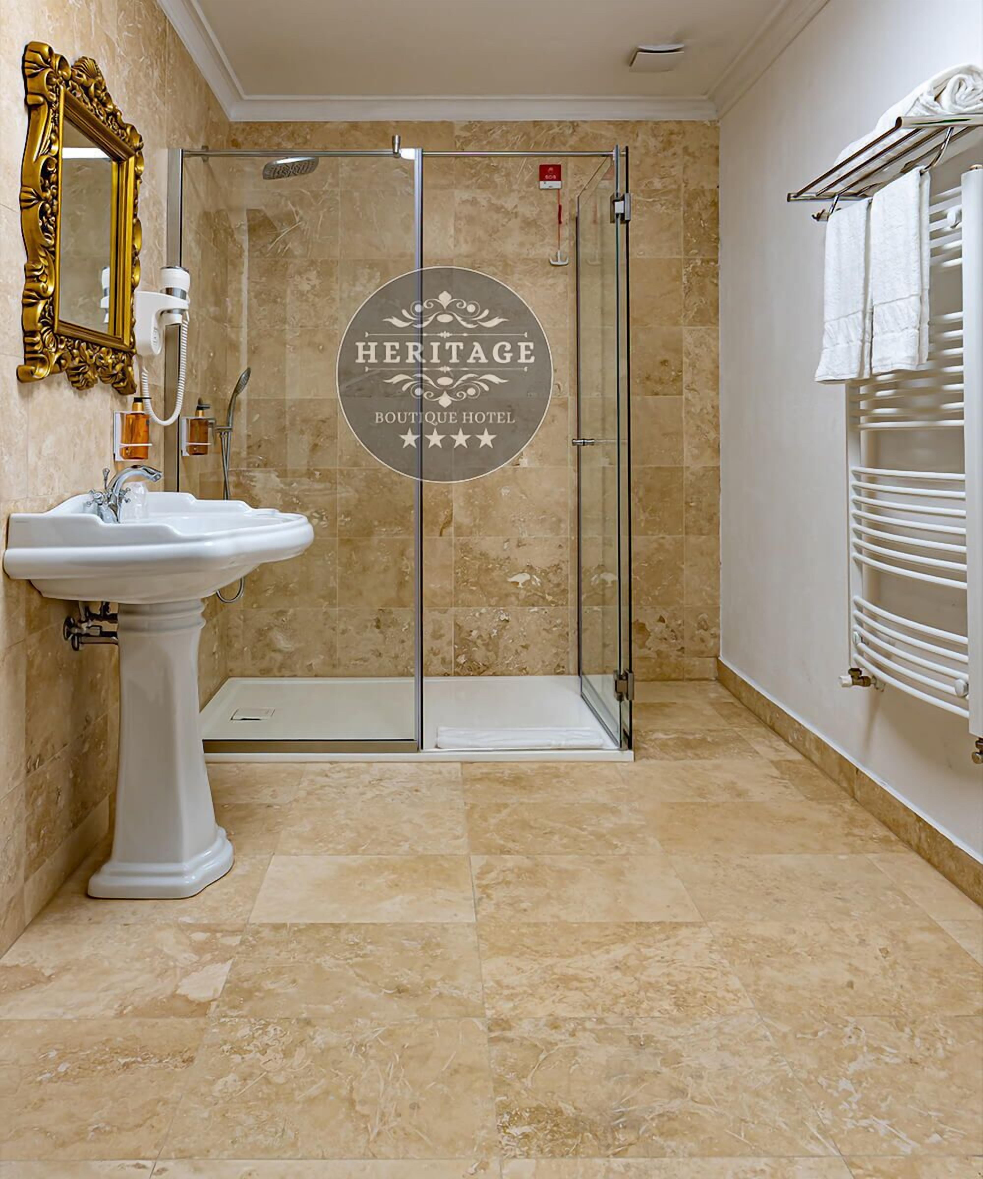 A bathroom with a glass shower enclosure, a pedestal sink, and a towel rack.