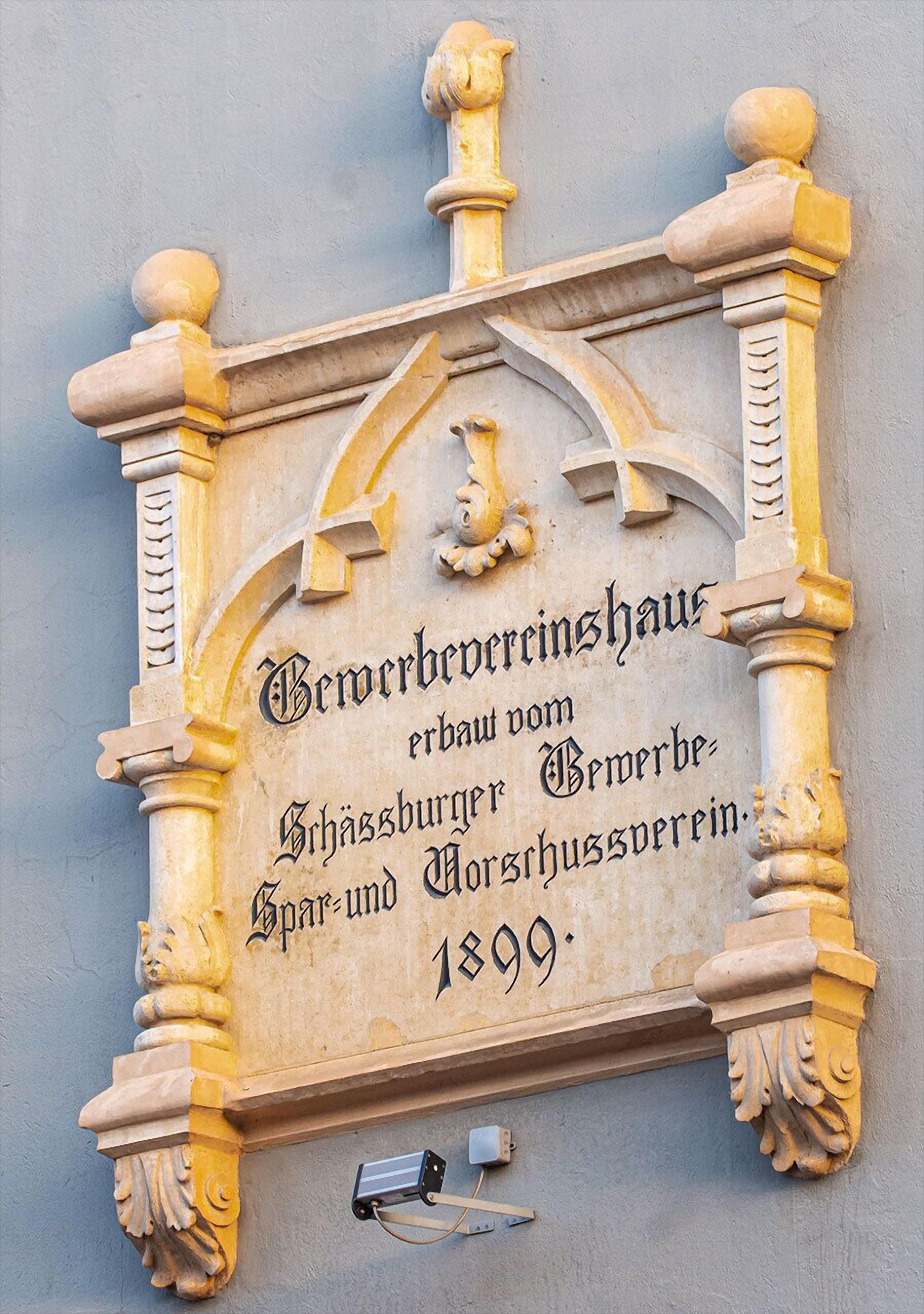 A carved stone plaque with text and architectural details, including a lion's head and columns.