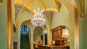 A grand hallway with a chandelier, a wooden reception desk, and a staircase leading to another level. - Heritage Boutique Hotel Sighisoara (Sighişoara)